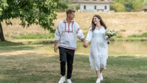 A joyful couple in traditional attire walking hand in hand on a sunny day.